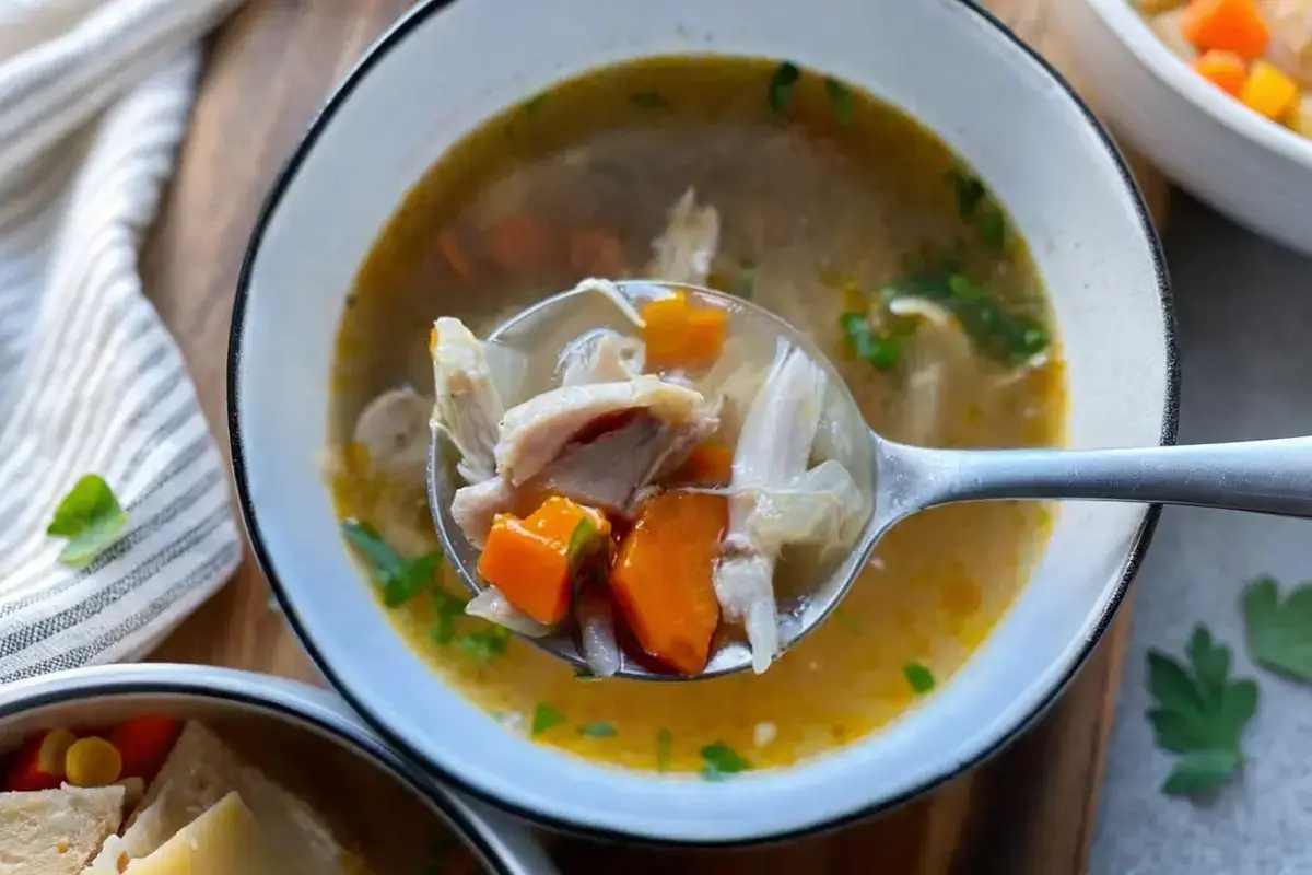 Homemade chicken drumstick soup with bone-in drumsticks and veggies in Dutch oven
